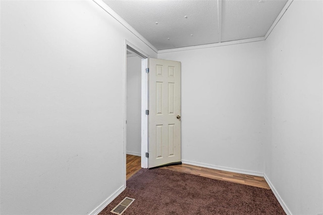 empty room with dark colored carpet and a textured ceiling