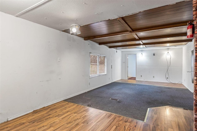 empty room with beamed ceiling and wood-type flooring