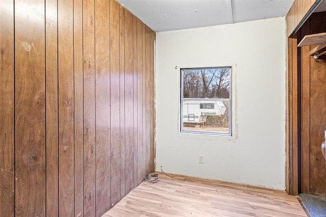 spare room with light hardwood / wood-style floors and wooden walls