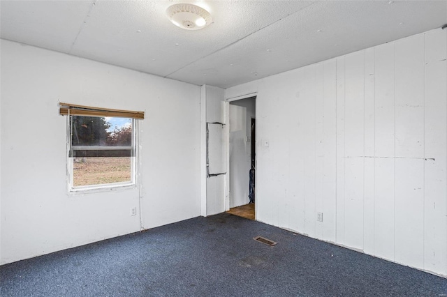 carpeted empty room with wood walls