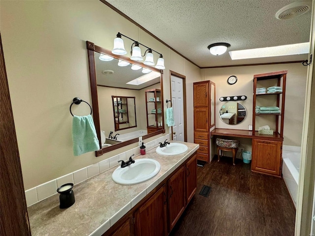 bathroom with hardwood / wood-style floors, vanity, a bathing tub, a skylight, and a textured ceiling