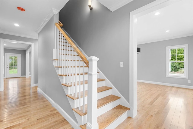 stairs featuring wood-type flooring, plenty of natural light, and ornamental molding