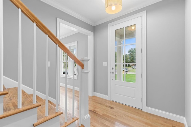 entrance foyer featuring light hardwood / wood-style floors, a wealth of natural light, and ornamental molding