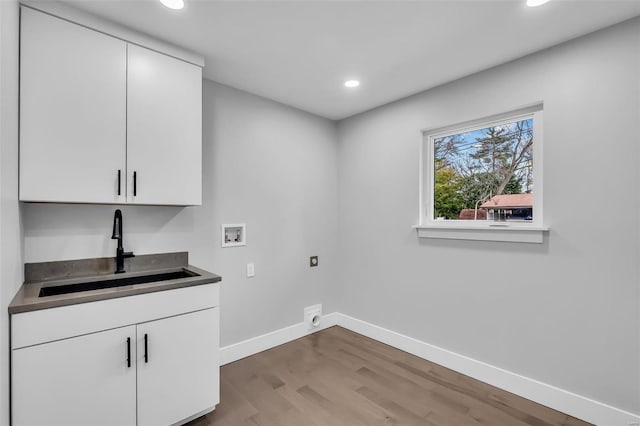 clothes washing area with cabinets, washer hookup, hookup for an electric dryer, sink, and wood-type flooring