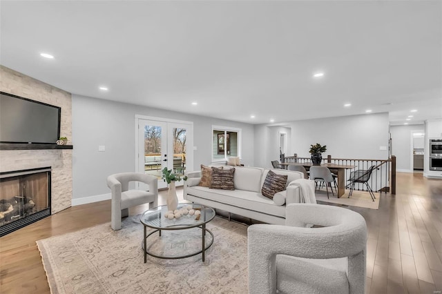 living room featuring a stone fireplace and light hardwood / wood-style floors