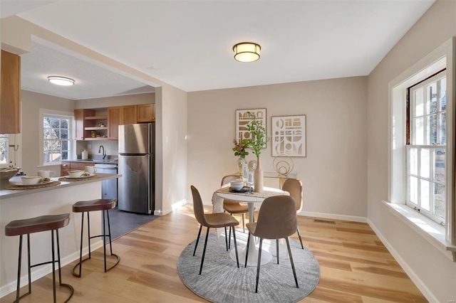 dining area featuring plenty of natural light, sink, and light hardwood / wood-style flooring