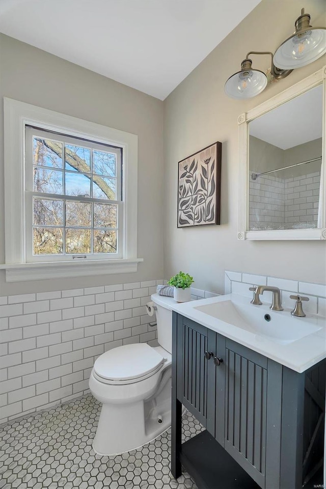 bathroom featuring tile patterned flooring, vanity, tile walls, and toilet