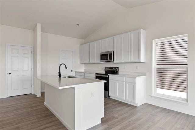 kitchen with range with electric cooktop, sink, white cabinetry, lofted ceiling, and a center island with sink