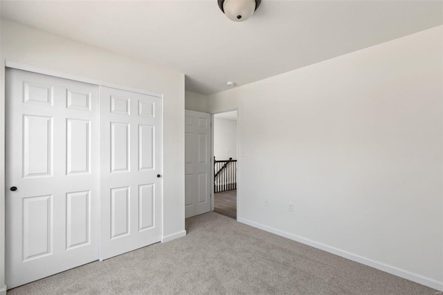 unfurnished bedroom featuring light carpet and a closet