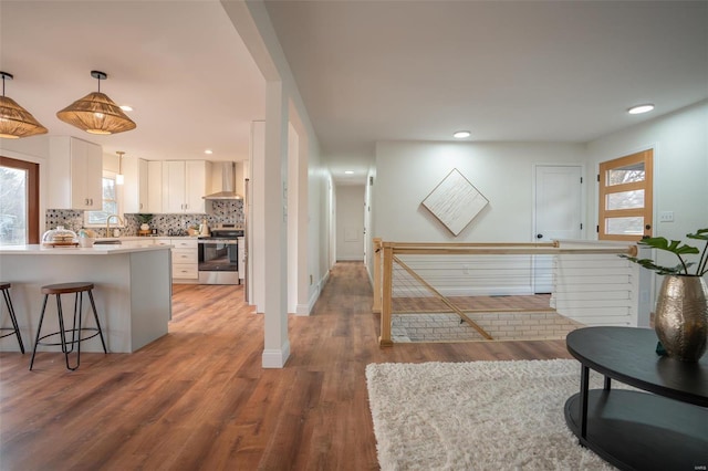 kitchen with pendant lighting, tasteful backsplash, white cabinetry, electric range, and wall chimney exhaust hood