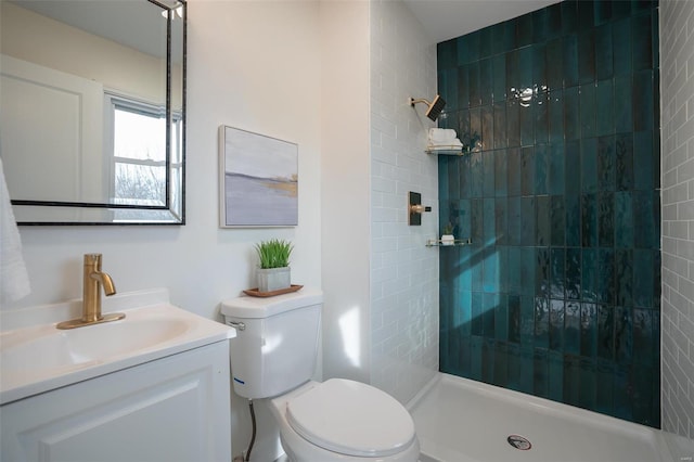 bathroom with vanity, toilet, and a tile shower