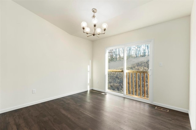 spare room with dark wood-type flooring and a notable chandelier