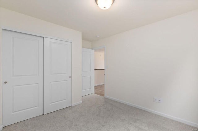 unfurnished bedroom with light colored carpet and a closet