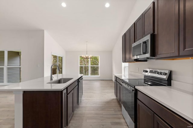 kitchen with a center island with sink, light hardwood / wood-style flooring, stainless steel appliances, and a chandelier