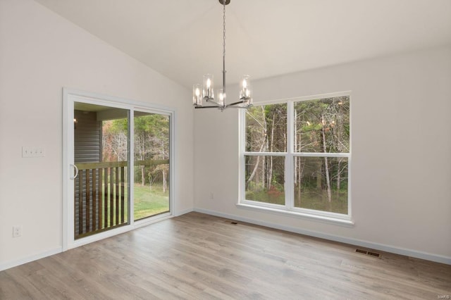 unfurnished dining area featuring an inviting chandelier, light hardwood / wood-style flooring, plenty of natural light, and lofted ceiling