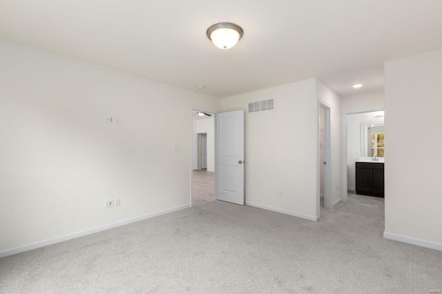 unfurnished bedroom featuring light colored carpet and ensuite bath