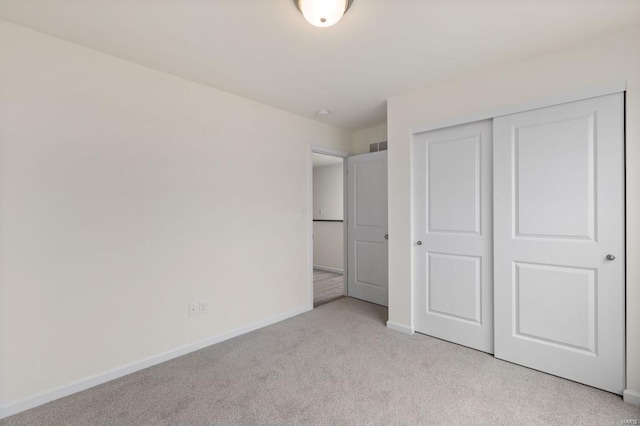 unfurnished bedroom with light colored carpet and a closet