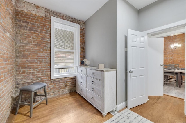 hallway featuring brick wall and light hardwood / wood-style floors