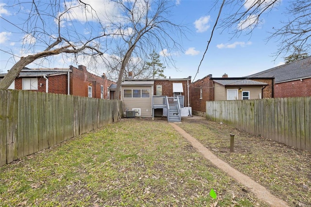 rear view of property with a yard, central AC, and a wooden deck