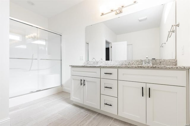 bathroom featuring hardwood / wood-style flooring, vanity, and a shower with shower door