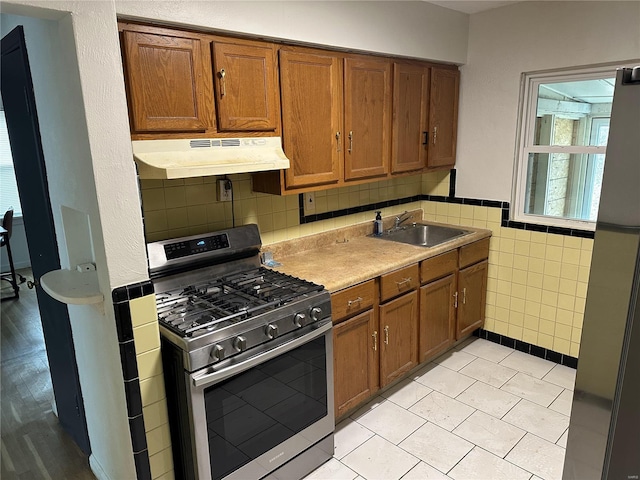 kitchen with light tile patterned flooring, gas stove, tile walls, and sink