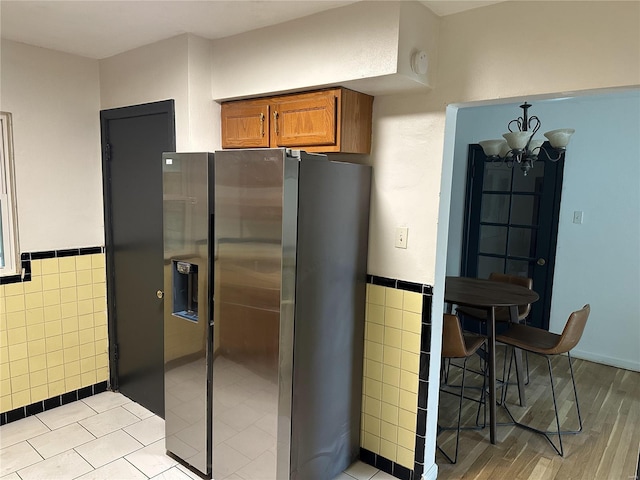 kitchen with a chandelier, stainless steel fridge, and tile walls