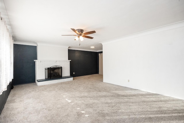 unfurnished living room featuring ceiling fan, crown molding, carpet floors, and a brick fireplace