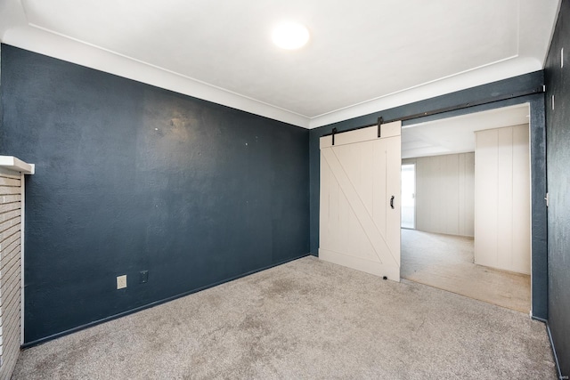 unfurnished room with a barn door and carpet floors