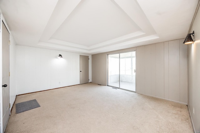 empty room with light colored carpet and a tray ceiling