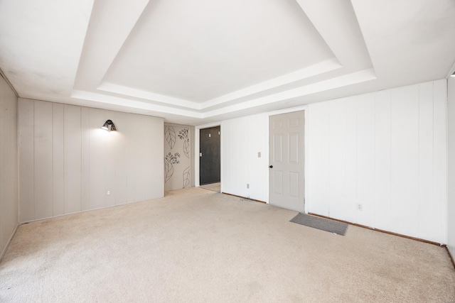 carpeted empty room featuring a tray ceiling