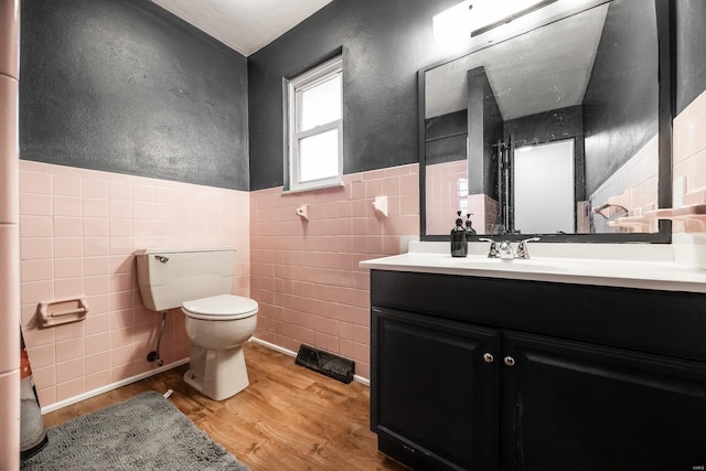 bathroom featuring vanity, toilet, wood-type flooring, and tile walls