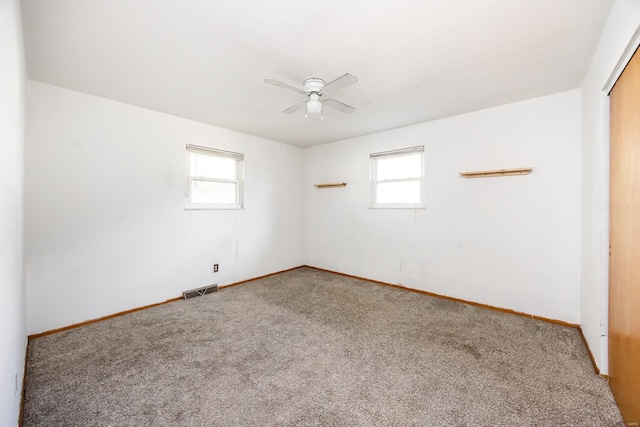 carpeted spare room featuring ceiling fan and a wealth of natural light