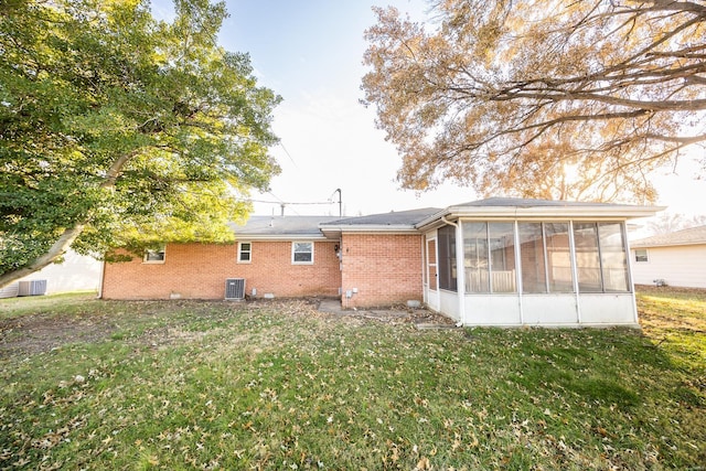 back of property with a sunroom, a yard, and central air condition unit