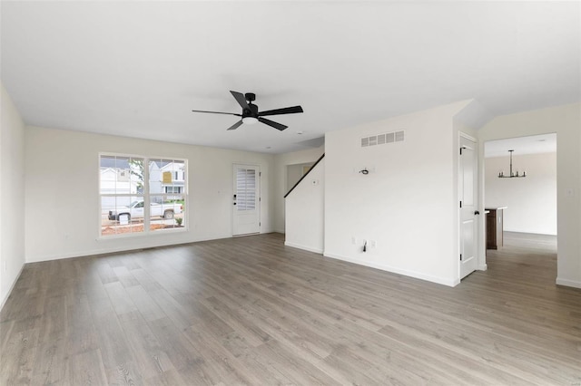 unfurnished living room featuring hardwood / wood-style floors and ceiling fan with notable chandelier