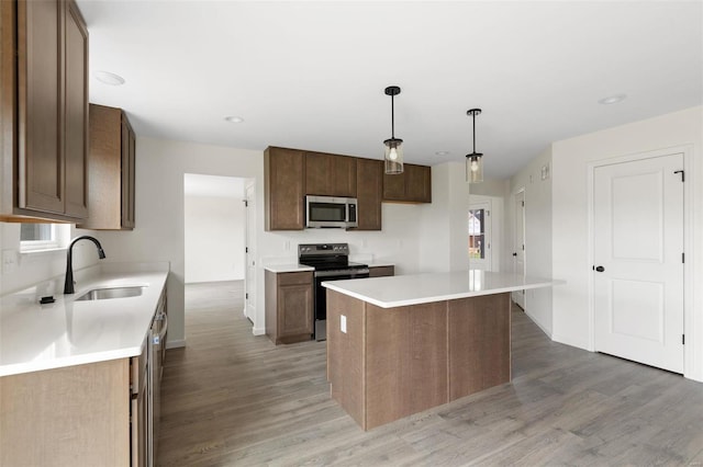 kitchen featuring a center island, stainless steel appliances, hanging light fixtures, and light hardwood / wood-style floors