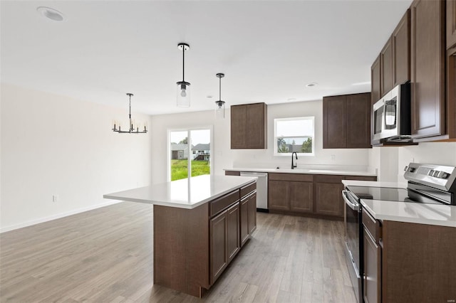 kitchen featuring stainless steel appliances, a chandelier, decorative light fixtures, light hardwood / wood-style floors, and a kitchen island