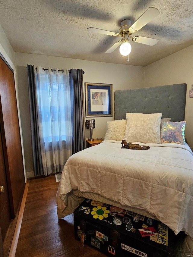 bedroom with dark hardwood / wood-style floors, ceiling fan, a textured ceiling, and a closet