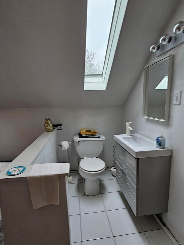 bathroom featuring tile patterned flooring, vanity, toilet, and lofted ceiling with skylight