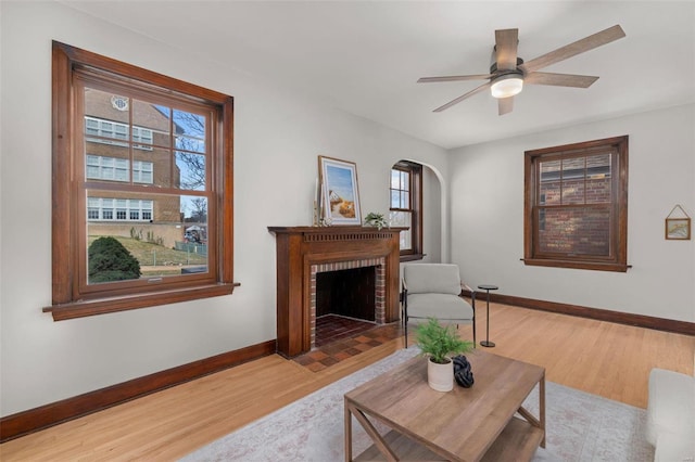 living room with plenty of natural light, ceiling fan, light wood-type flooring, and a fireplace