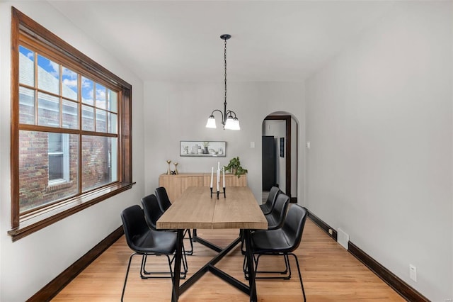 dining area with light hardwood / wood-style floors and an inviting chandelier