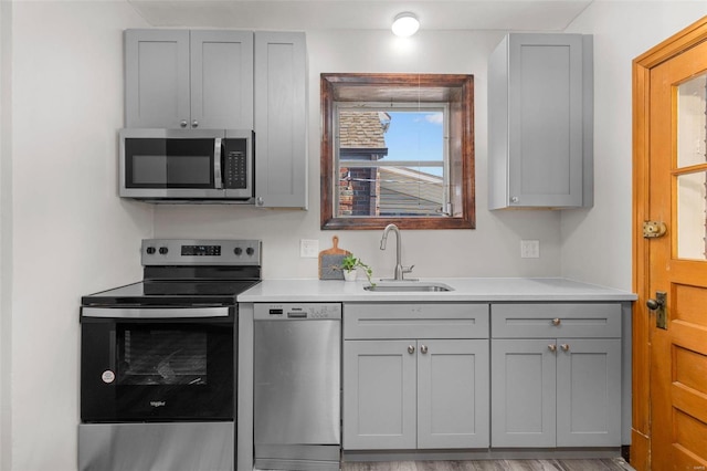 kitchen featuring gray cabinetry, sink, appliances with stainless steel finishes, and light hardwood / wood-style flooring