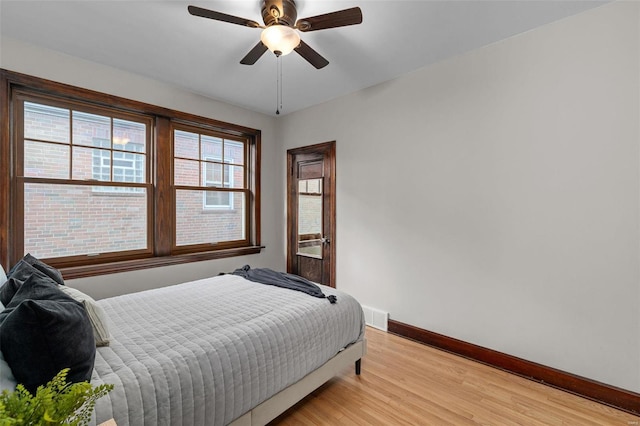 bedroom with multiple windows, ceiling fan, and light wood-type flooring