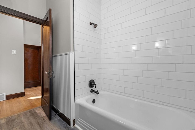 bathroom with hardwood / wood-style flooring and tiled shower / bath