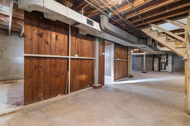 basement with heating unit, wood walls, and gas water heater