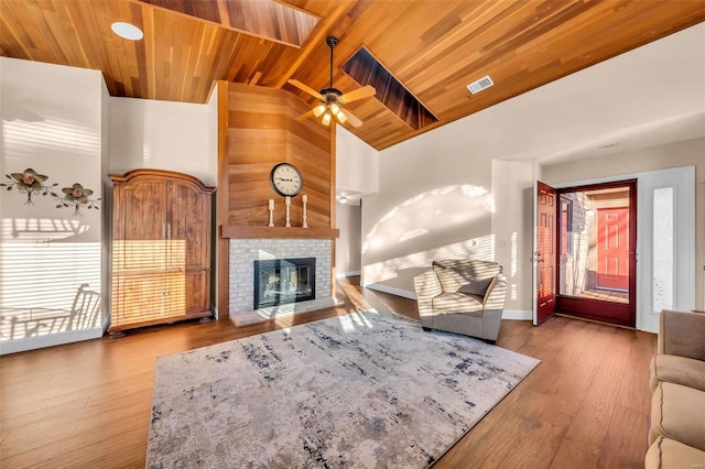 living area featuring high vaulted ceiling, a fireplace, wood finished floors, visible vents, and wood ceiling