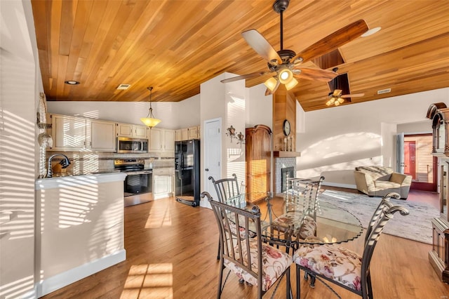 dining room with light wood-style floors, wood ceiling, a fireplace, and visible vents