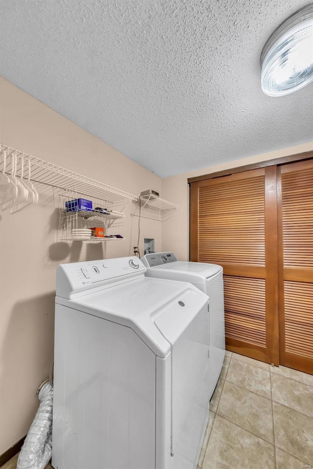 laundry area with laundry area, independent washer and dryer, a textured ceiling, and light tile patterned floors