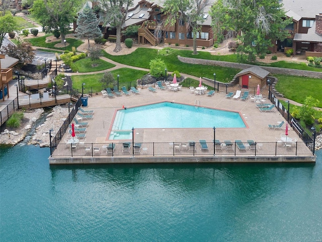 pool featuring a patio area, a water view, and fence