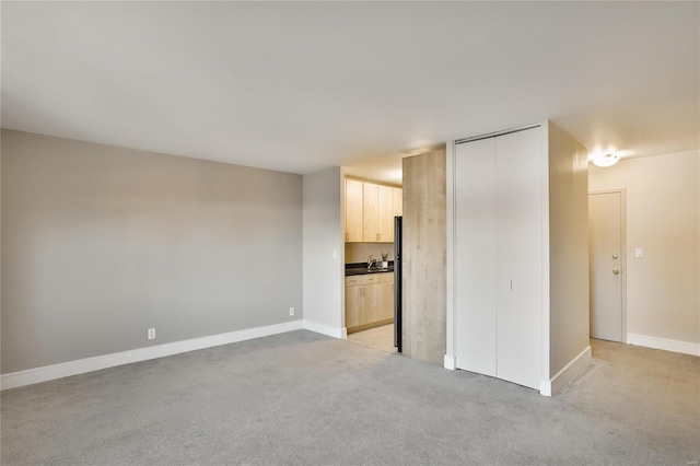 unfurnished living room featuring light carpet and sink