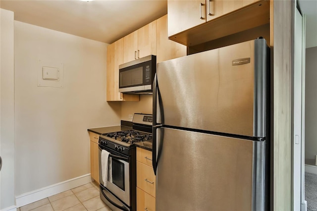 kitchen with light brown cabinets, light tile patterned flooring, and appliances with stainless steel finishes